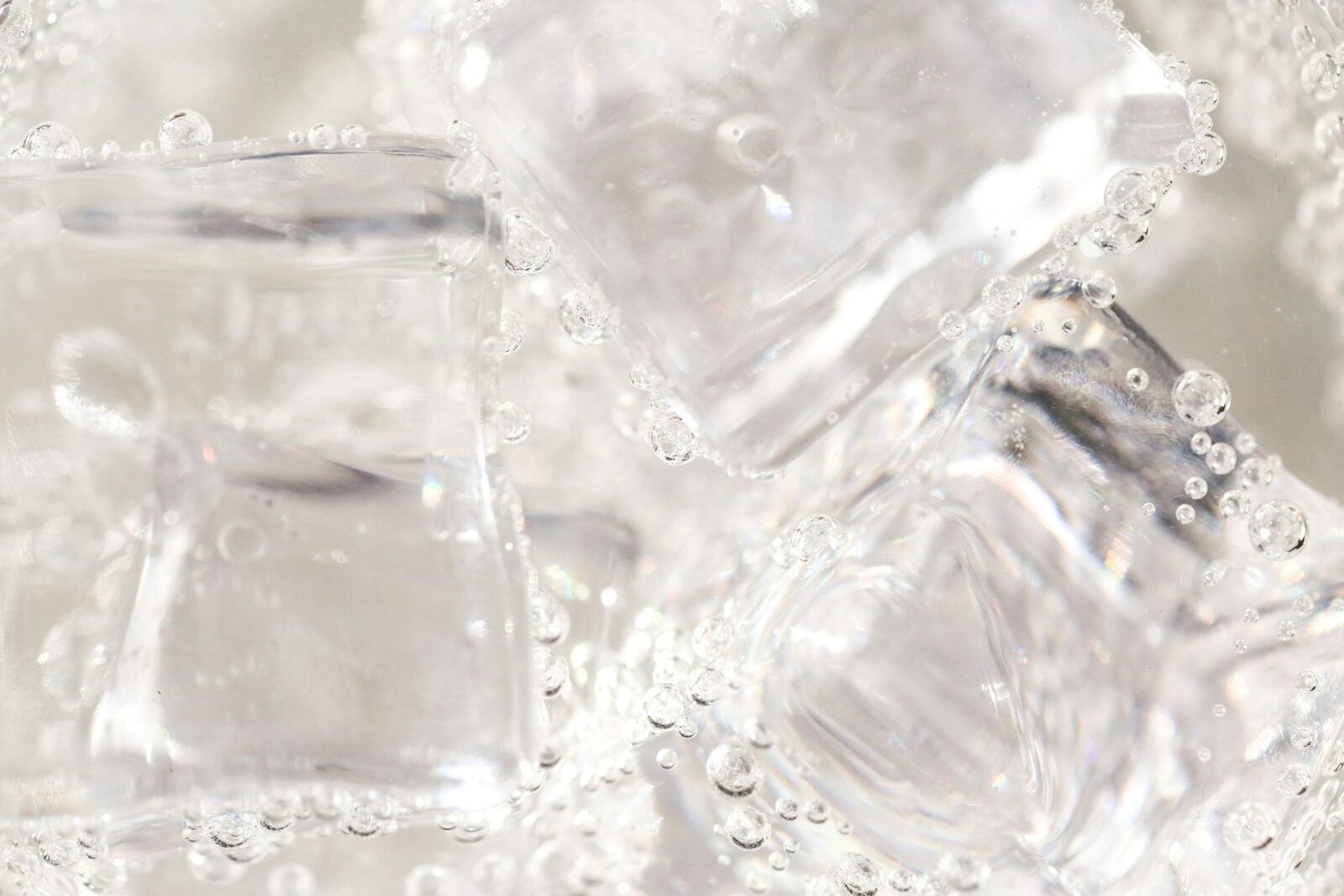 A clear glass container with ice cubes on a white textile — clean minimalist still life.